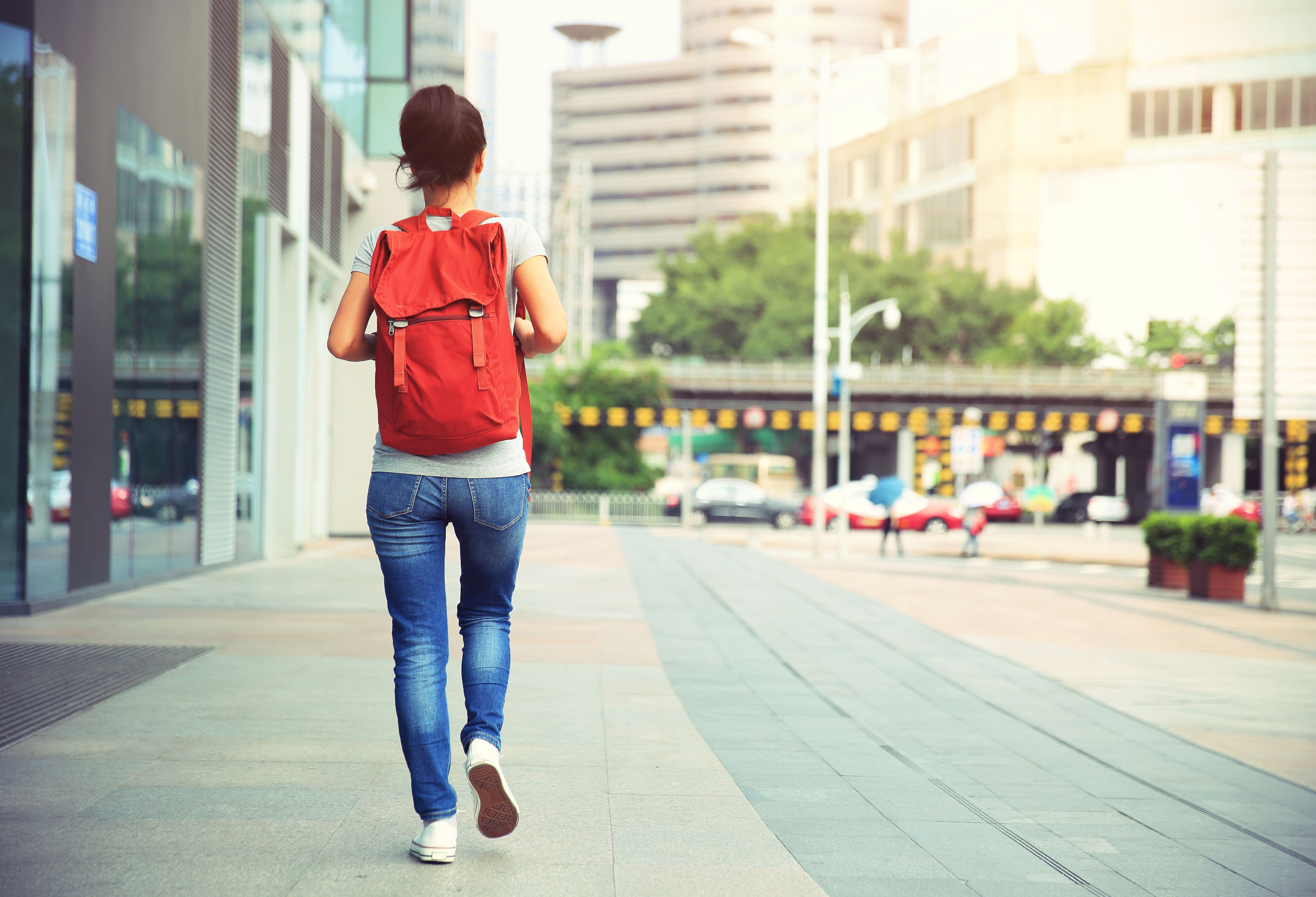 woman-with-rucksack-walking-on-street-PEJXBSD-min
